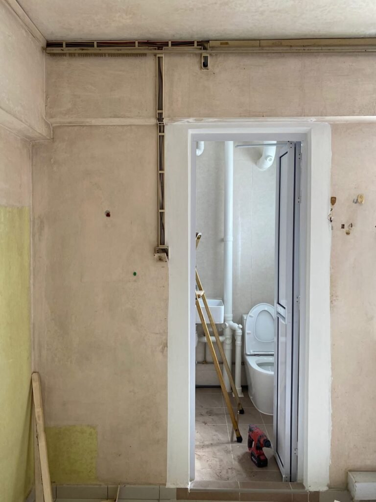 Bathroom wall with pipes and wiring prepared for water heater installation in Singapore