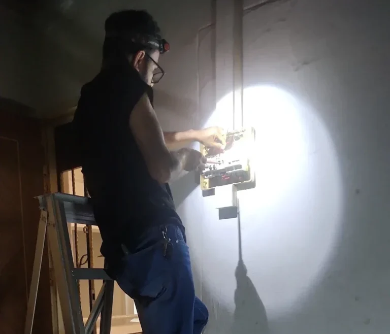 Emergency electrician working by torchlight during a power failure at night in Singapore