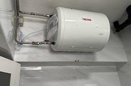 Close-up of a horizontal storage water heater with stainless steel pipe fittings in a Singapore bathroom